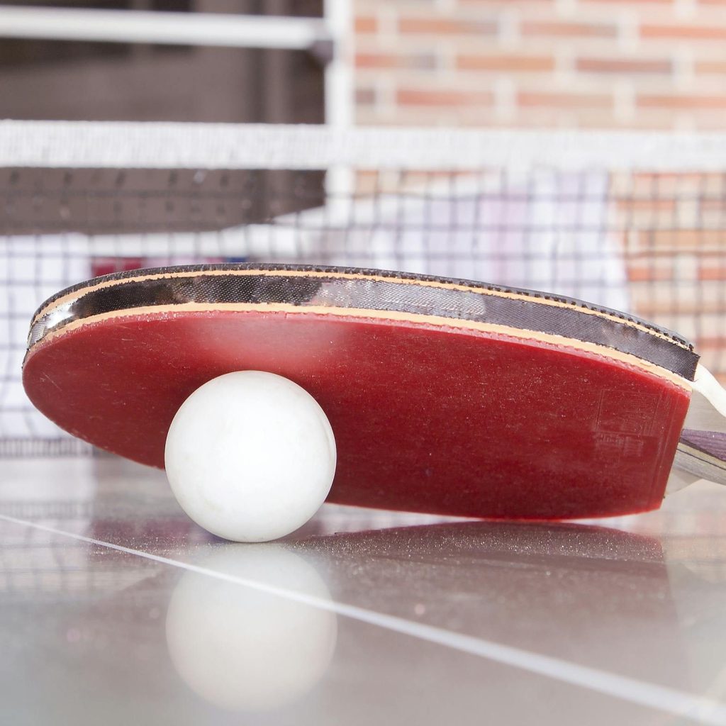 White Pingpong Ball Beneath Red Table Tennis Paddle